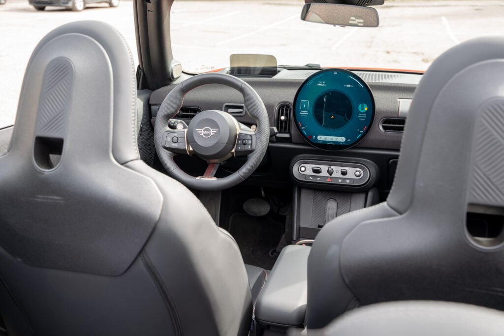 Koeajo: Mini Cooper Cabrio on 60 000 euron kesälelu, jota järki ei osaa selittää Mini Cooper Cabrion ohjaamo kuvattuna takaistuimelta, edessä pyöreä OLED-näyttö ja ohjauspyörä.