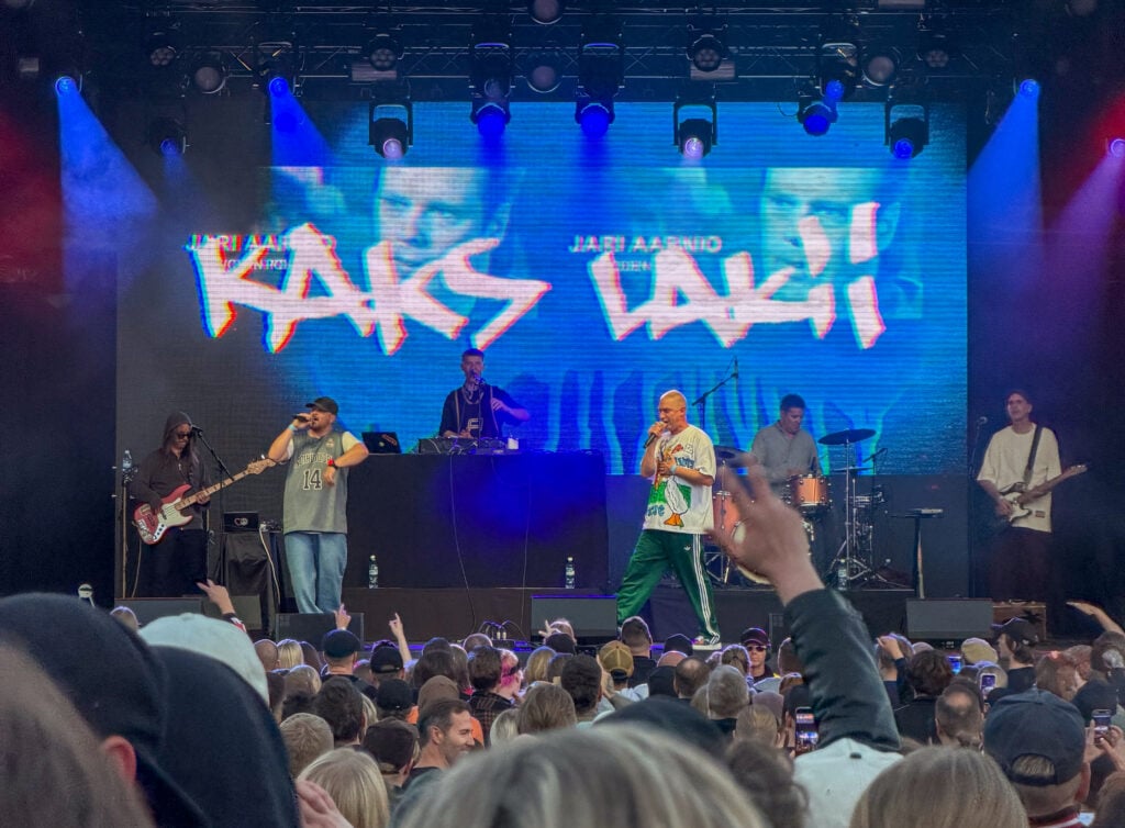Konserttiarvio: Loppuunmyyty Punainen tiili -keikka oli aselepo Asan oman historian kanssa Asa esittää Punainen tiili -juhlakonsertissa Kaks lakii kappaleen, taustalla kuvia Jari Aarniosta