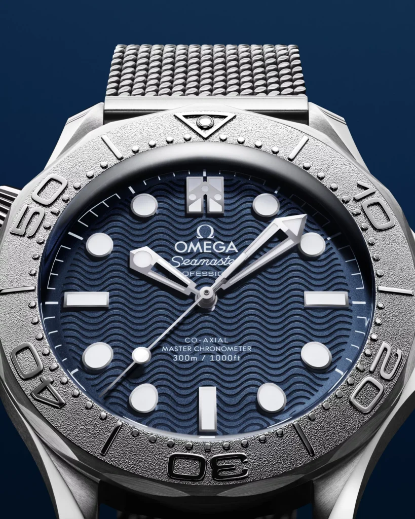 Omega julkaisi uuden James Bond -kellon – ensi kertaa tiuku myös pahiksille Lähikuva Omega Seamaster James Bond Editionin sinisestä aaltokuvioisesta kellotaulusta ja titaanisesta sukelluskehästä.