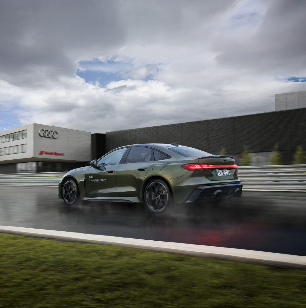 Justsiks koki Audi driving experiencen Nürburgringillä: märkää rataa ja unohtumaton ajopäivä Vihreä Audi RS e-tron GT ajaa märällä radalla Audi Sport -rakennuksen ohi.